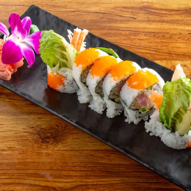 Aiki Sushi & Ramen's sushi roll with bright orange roe, lettuce, and fish, garnished with a purple orchid.